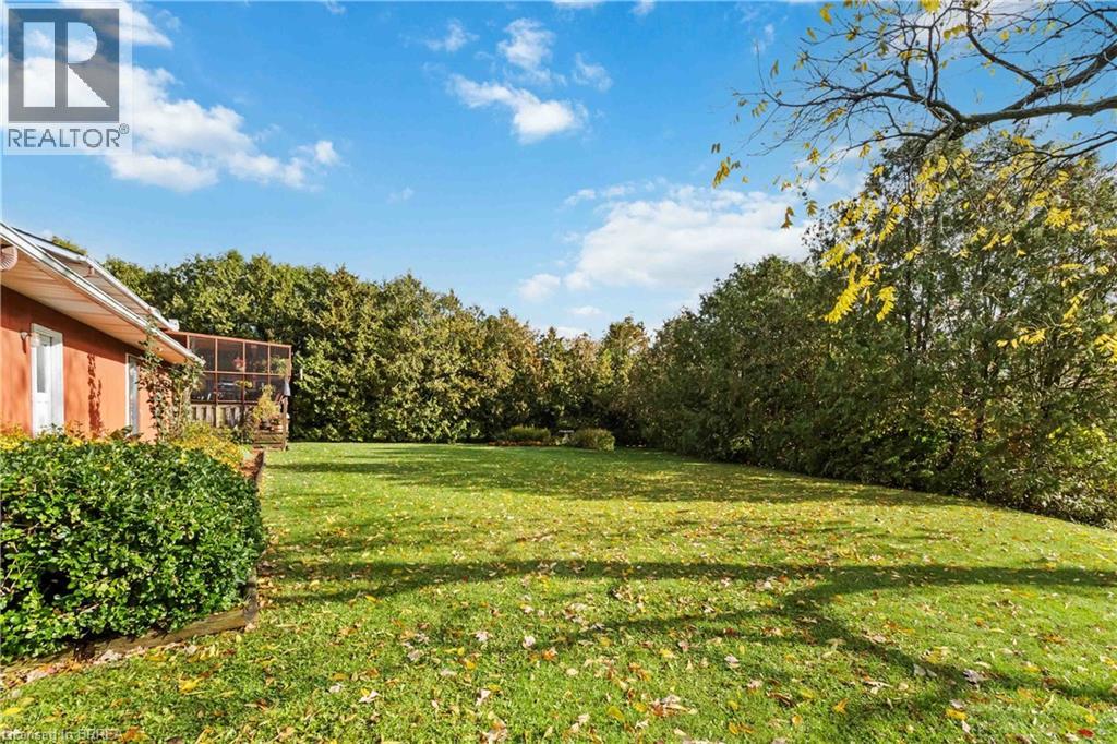 View of green lawn with a sunroom and a view of trees