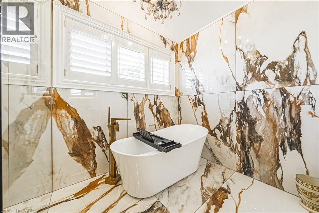 Full bath with healthy amount of natural light, stone wall, marble tiled flooring, and a soaking tub