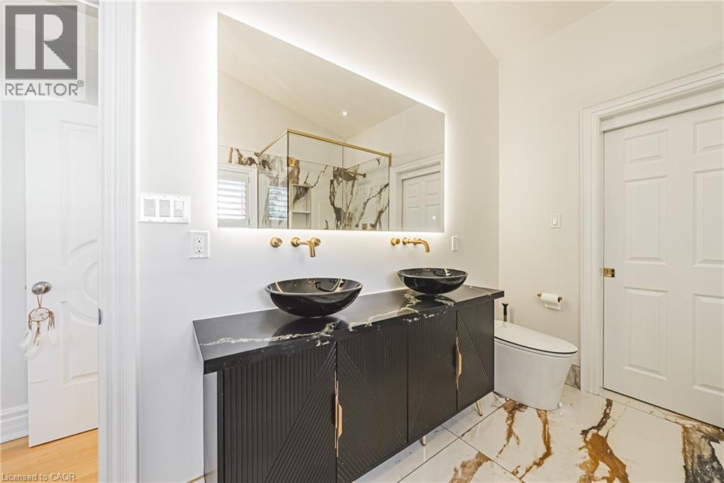 Full bath with double vanity and a marble finish shower