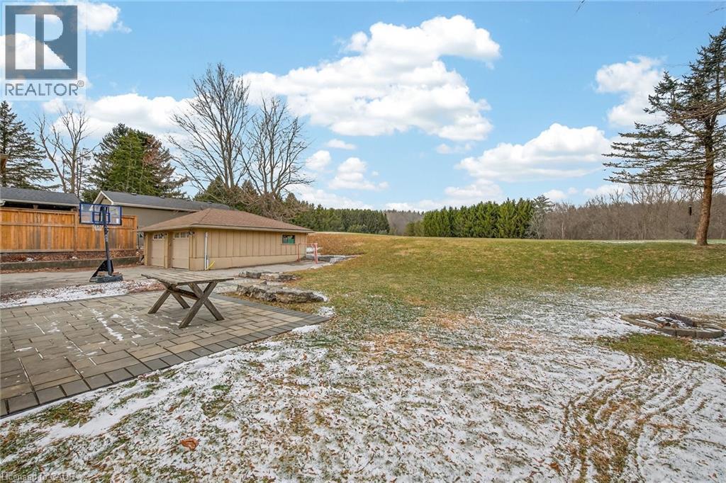 View of green lawn with a patio area and an outbuilding