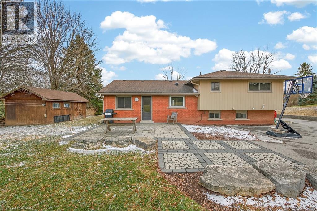 Back of house with a patio area, an outdoor structure, brick siding, and a lawn