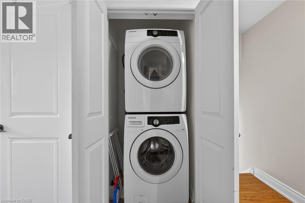 Laundry area with stacked washer and clothes dryer and light wood-type flooring