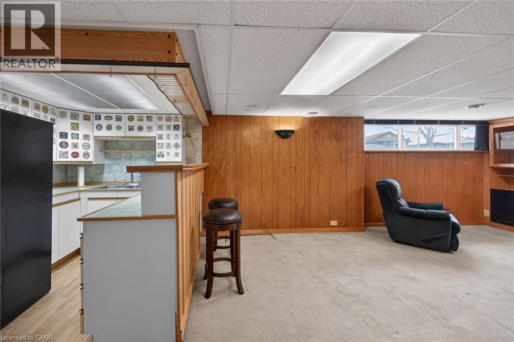 Bar area with freestanding refrigerator, white cabinetry, a paneled ceiling, light countertops, and wood walls