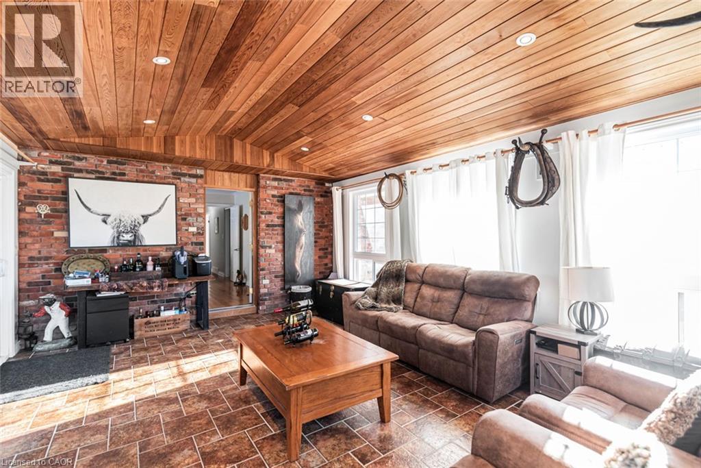 Living area with vaulted ceiling, brick wall, wood ceiling, and stone tile flooring
