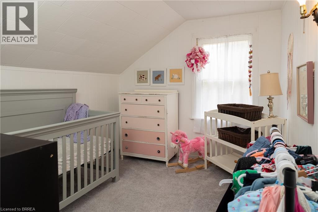 Bedroom with light carpet, vaulted ceiling, and a crib