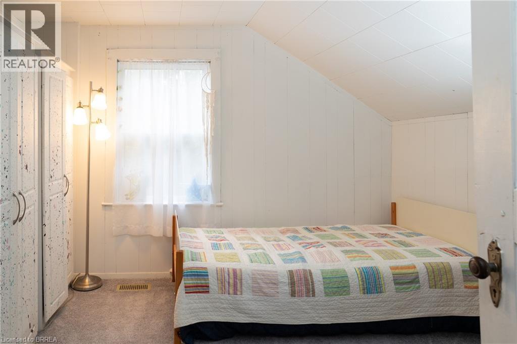 Bedroom featuring carpet, wooden walls, and vaulted ceiling