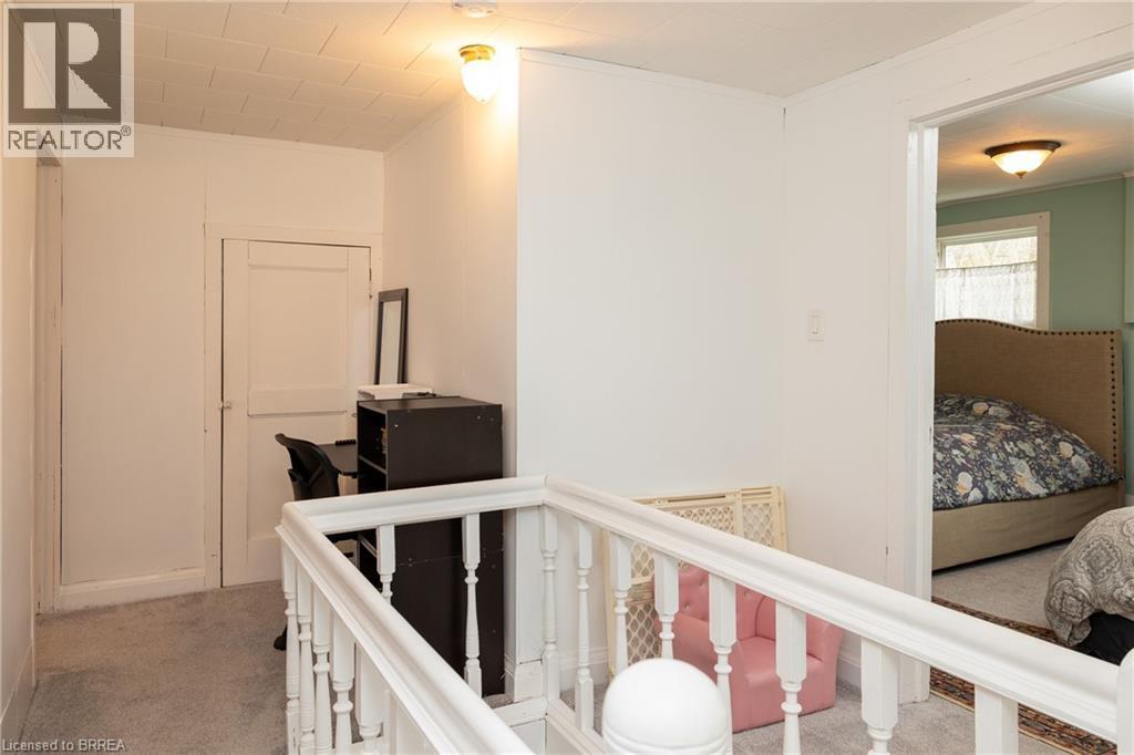Hallway featuring light carpet, an upstairs landing, and crown molding