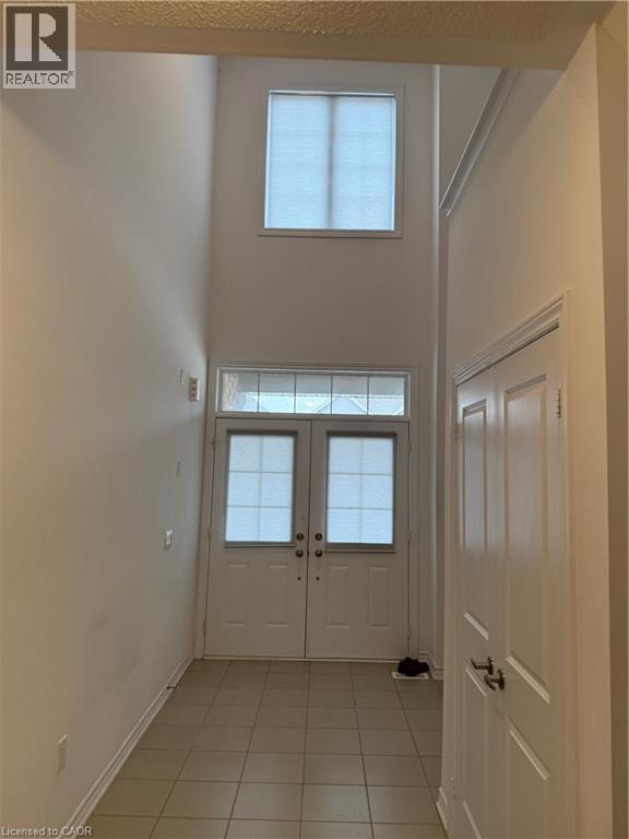 Doorway to outside with healthy amount of natural light, a high ceiling, and tile patterned floors