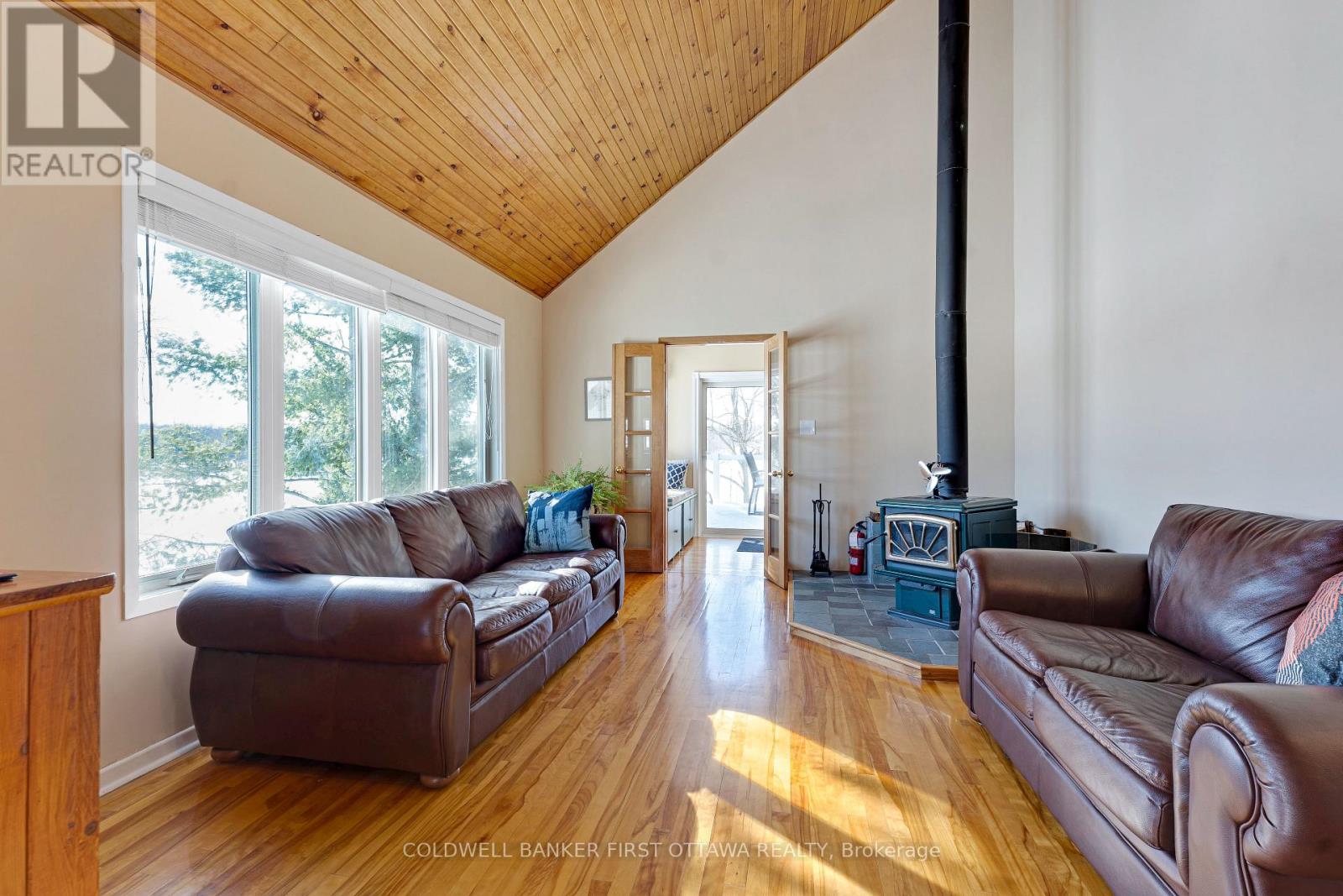 Familyroom woodstove & wall of windows facing lake
