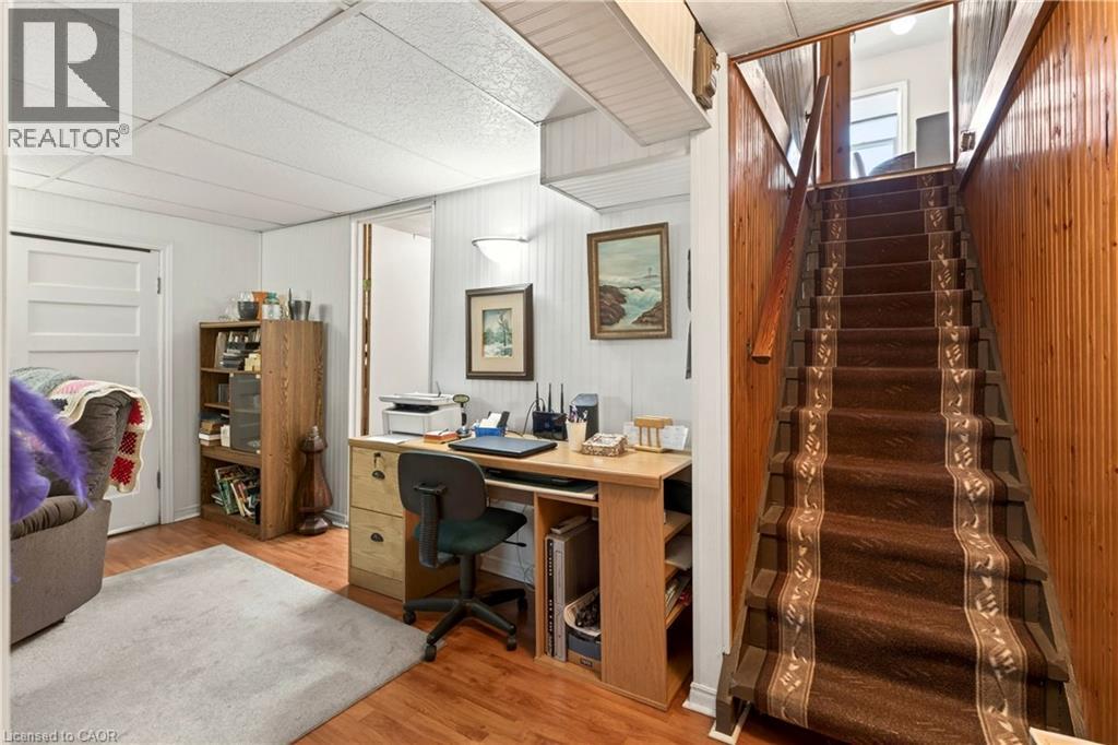 Office with light wood-style flooring, a drop ceiling, and wooden walls