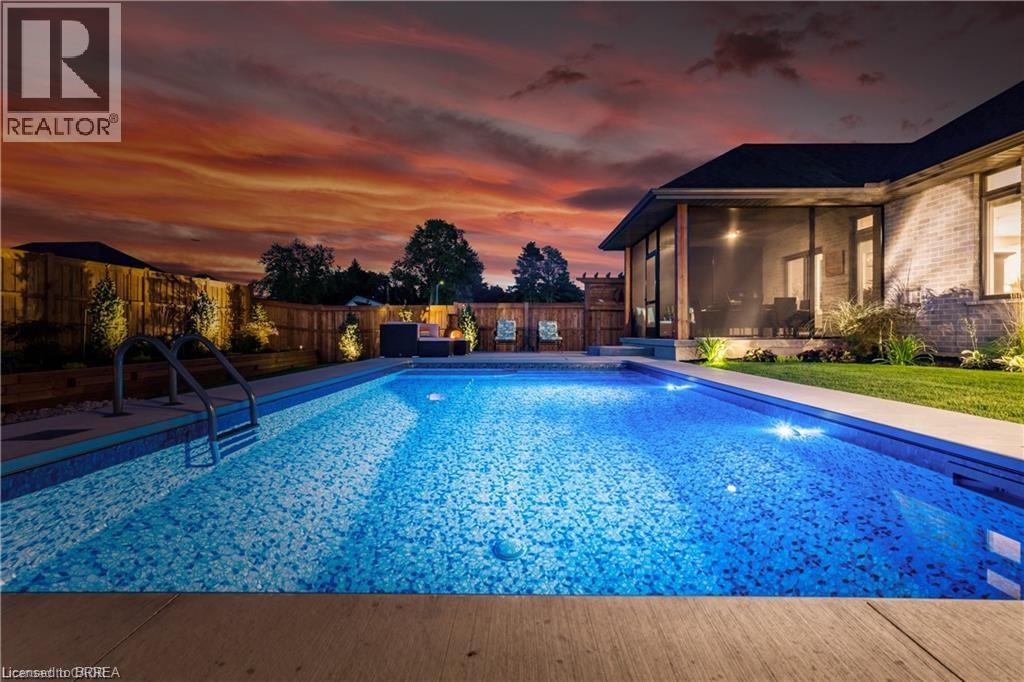 Pool at dusk featuring a fenced backyard, a sunroom, and a patio area