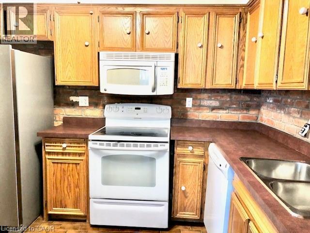 Kitchen featuring white appliances, dark countertops, and decorative backsplash
