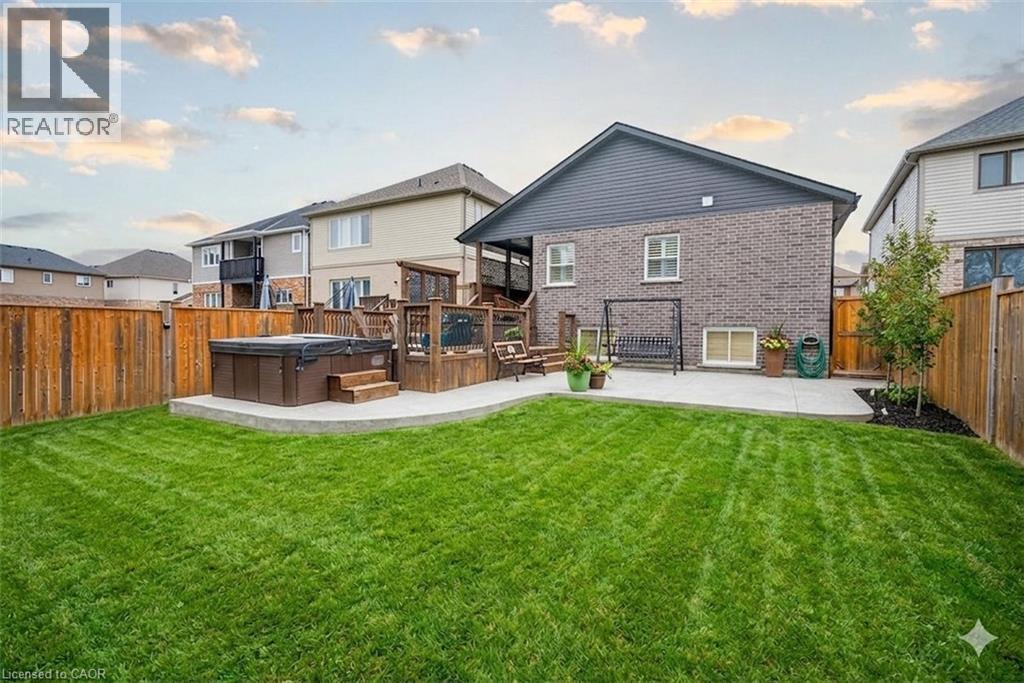 Rear view of property featuring a hot tub, a fenced backyard, and a patio area