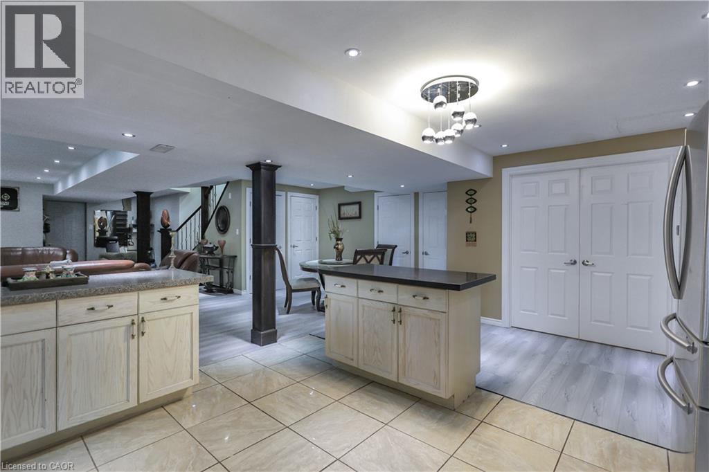 Kitchen with light wood finish cabinets, open floor plan, freestanding refrigerator, dark countertops, and light tile patterned flooring