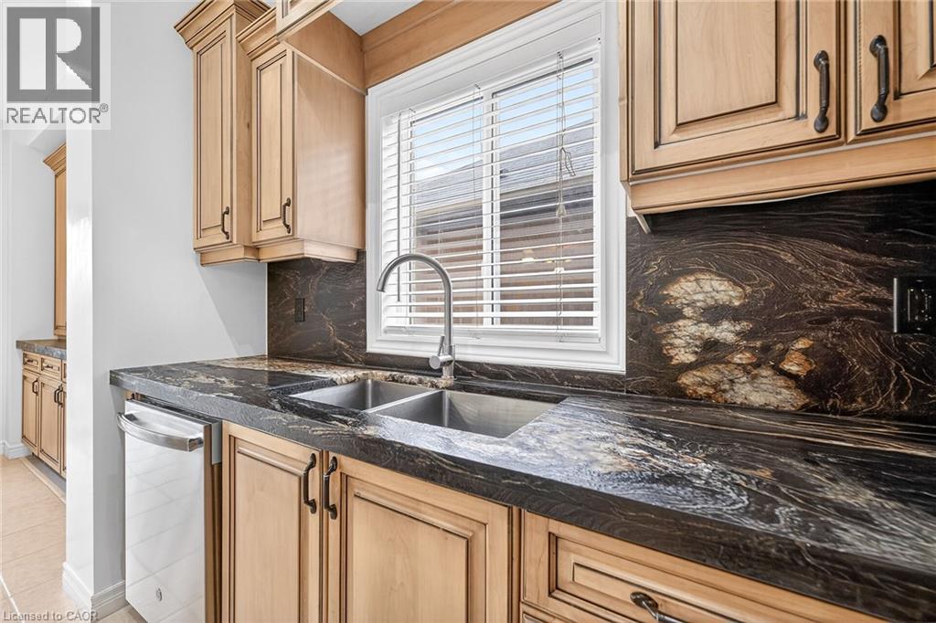 Kitchen with tasteful backsplash, dark stone counters, dishwasher, and light wood finish cabinets