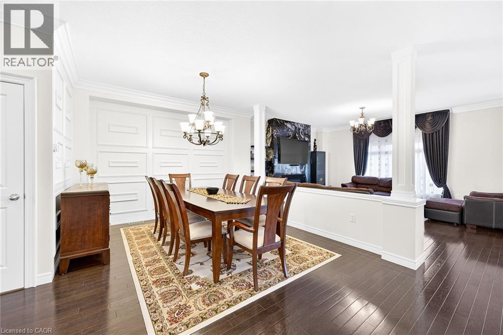 Dining room with a chandelier, ornamental molding, dark wood finished floors, and decorative columns