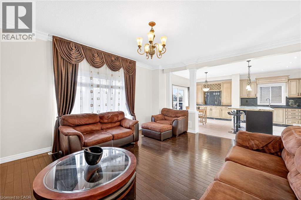 Living area featuring ornate columns, ornamental molding, light wood-style floors