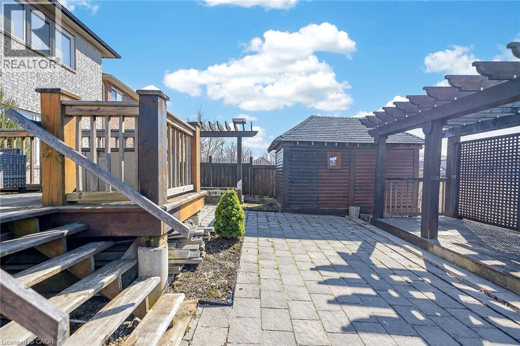 Fenced backyard featuring a wooden deck, an outdoor structure, and a patio