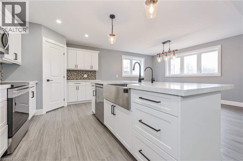 Kitchen featuring appliances with stainless steel finishes, light wood-style flooring, recessed lighting, decorative light fixtures, and tasteful backsplash