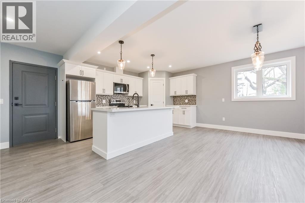 Kitchen with stainless steel appliances, backsplash, light countertops, recessed lighting, and white cabinetry