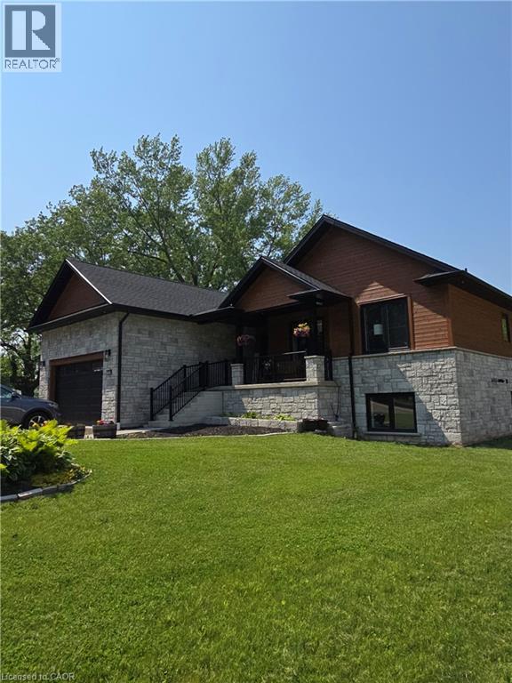 View of front facade featuring stone siding, an attached garage, and a front yard