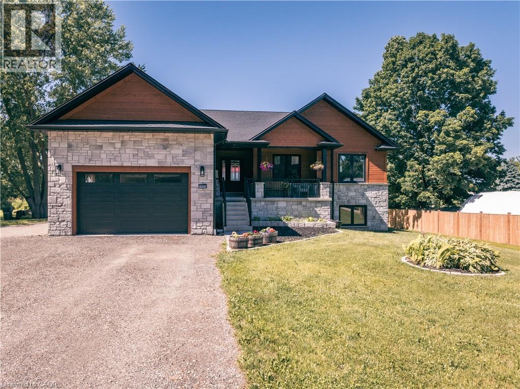 View of front facade featuring stone siding, covered porch, asphalt driveway, and an attached garage