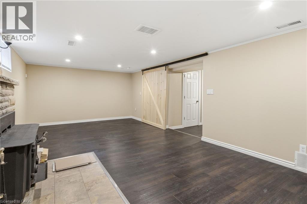 Unfurnished living room featuring a barn door, recessed lighting, dark wood-type flooring, and crown molding