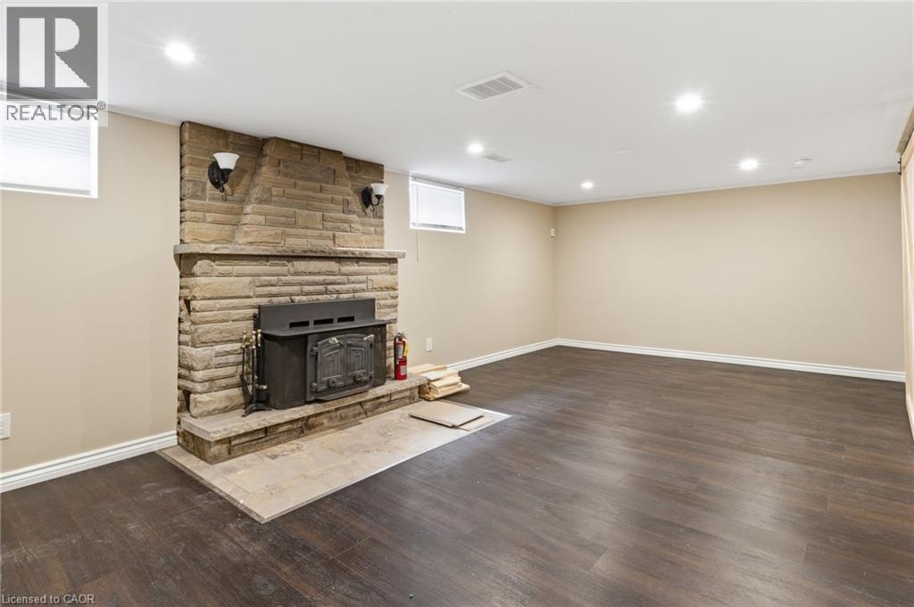 Unfurnished living room with dark wood-type flooring, recessed lighting, and a wood stove