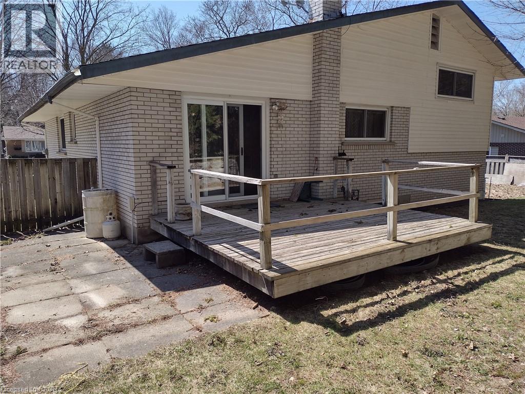 Back of house featuring brick siding, a chimney, and a wooden deck