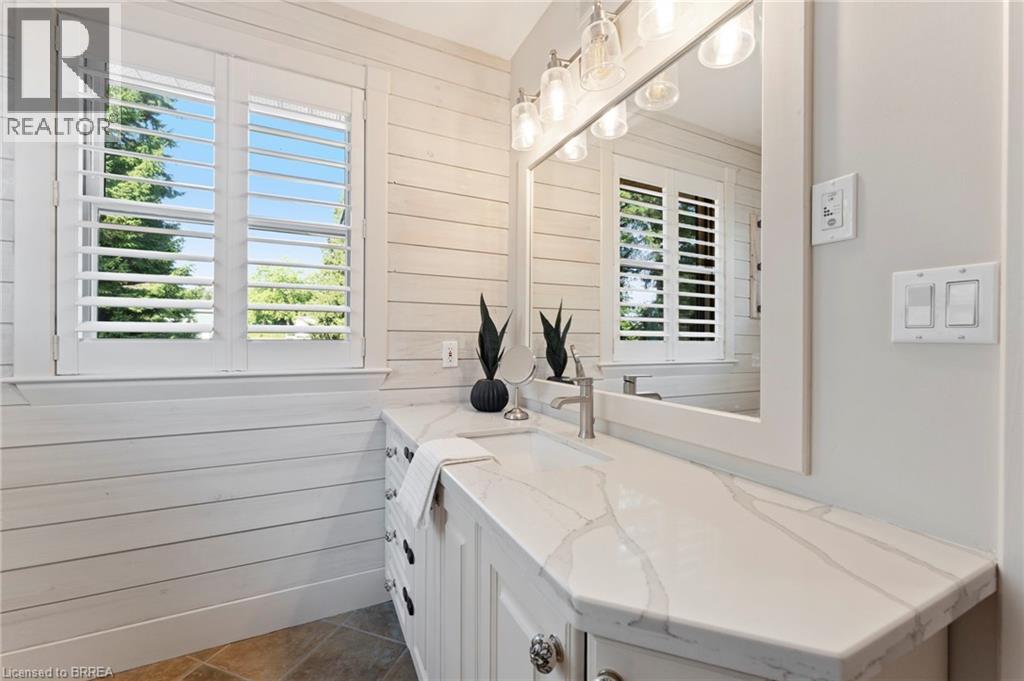 Bathroom with wooden walls, vanity, and dark tile patterned flooring