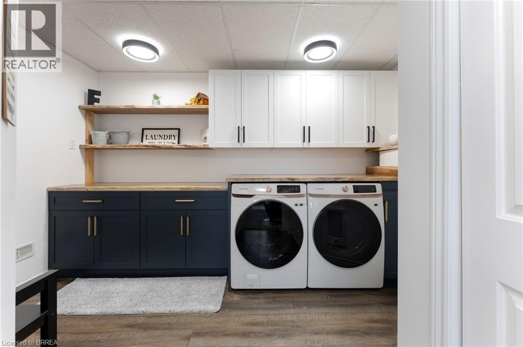Laundry area featuring washing machine and clothes dryer, cabinet space, dark wood-style flooring, and a drop ceiling