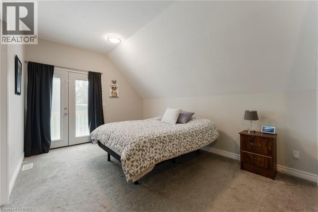 Bedroom featuring access to outside, french doors, vaulted ceiling, and light colored carpet