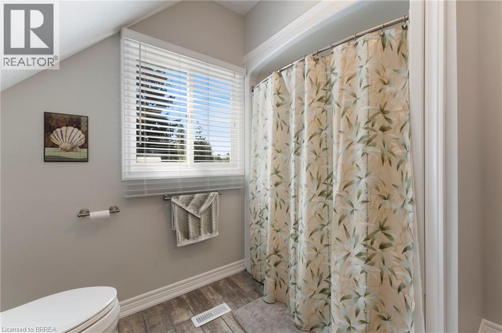 Full bathroom with a shower with shower curtain, wood finished floors, and lofted ceiling