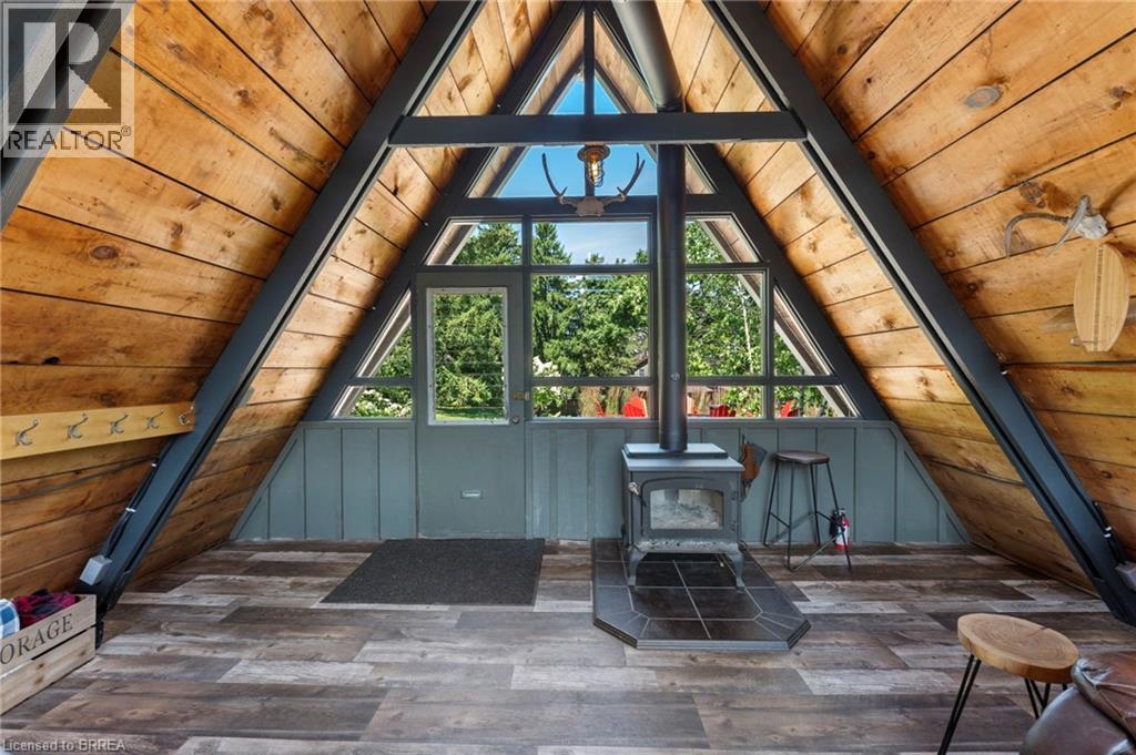 Additional living space with a wood ceiling with exposed beams, a wood stove, and wood finished floors