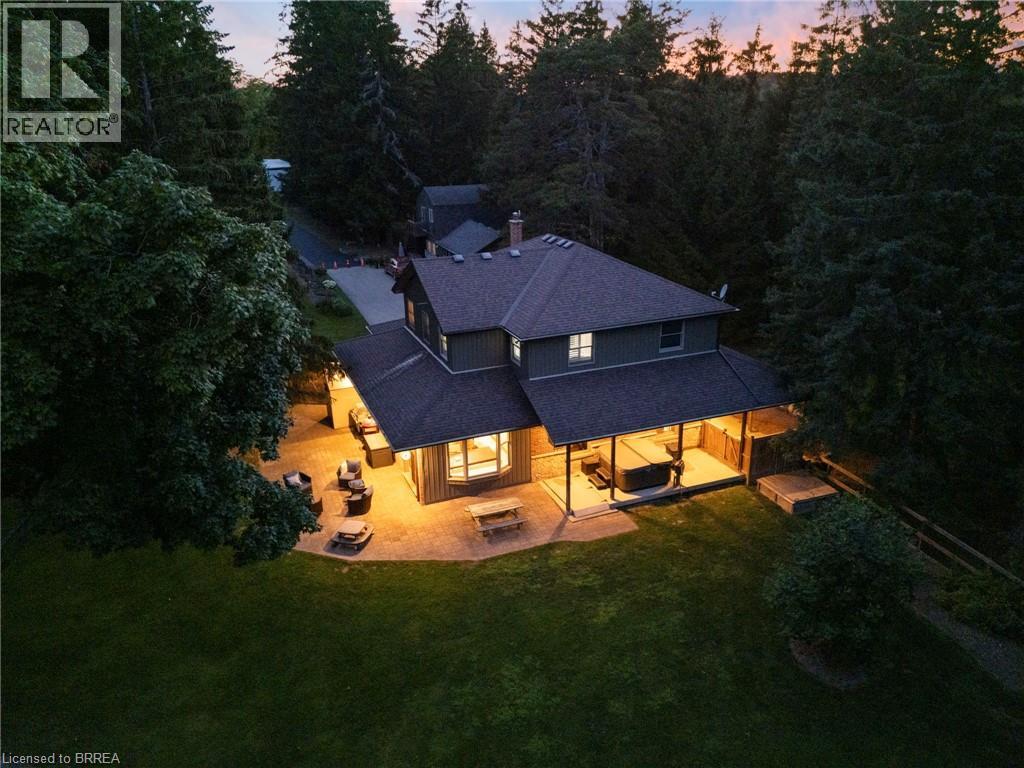 Rear view of house featuring a patio, a lawn, a shingled roof, and a chimney