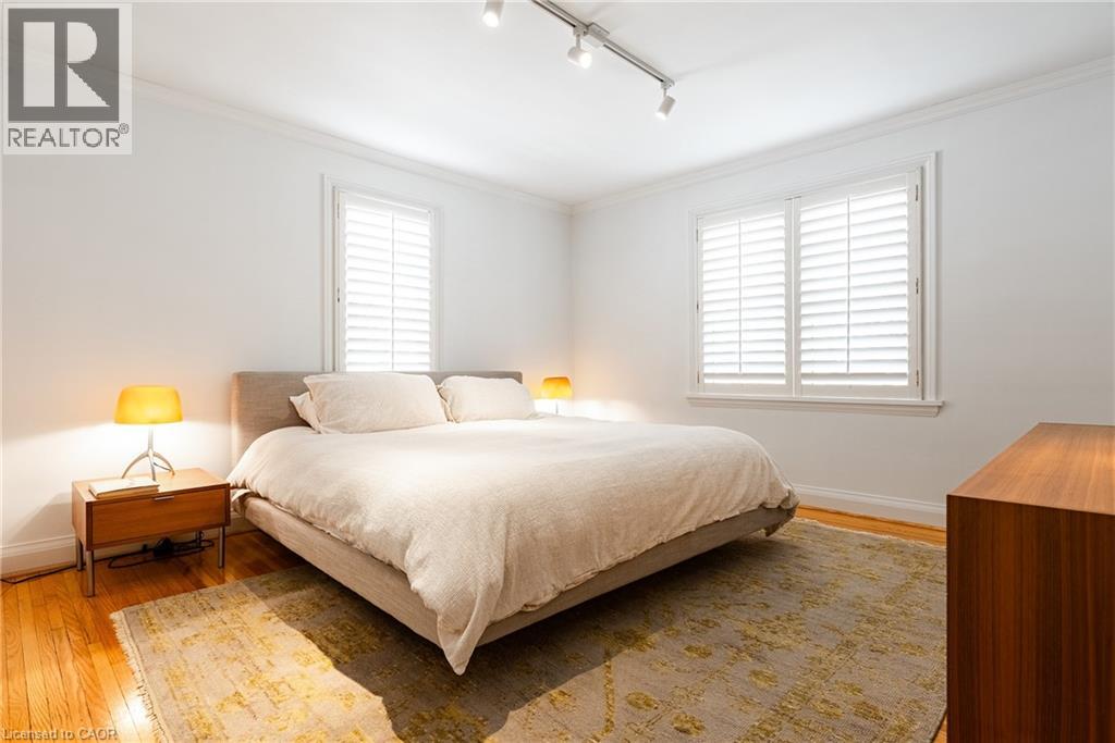 Bedroom with light wood finished floors, ornamental molding, and rail lighting