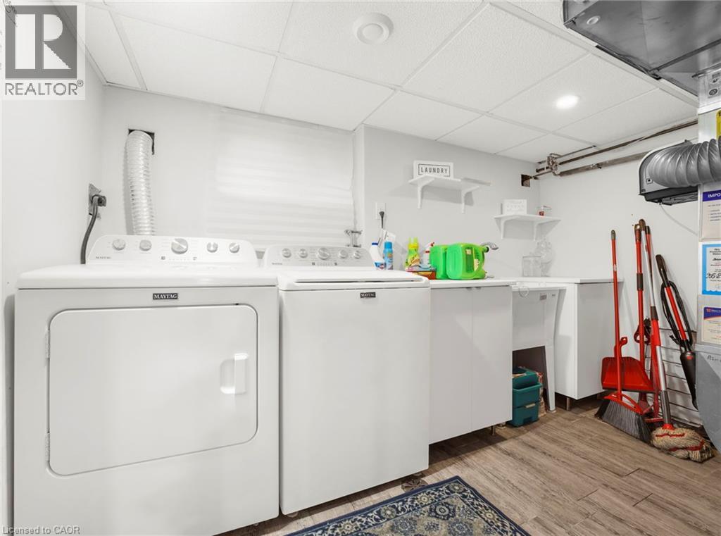 Laundry area featuring a paneled ceiling, washer and clothes dryer, and light wood finished floors
