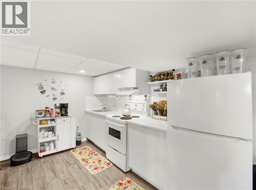 Kitchen featuring white appliances, white cabinets, open shelves, light wood finished floors, and a paneled ceiling