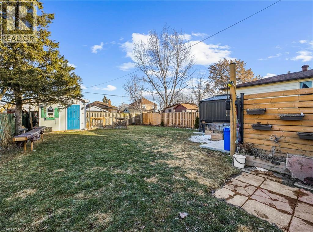 Fenced backyard featuring a storage unit and a residential view
