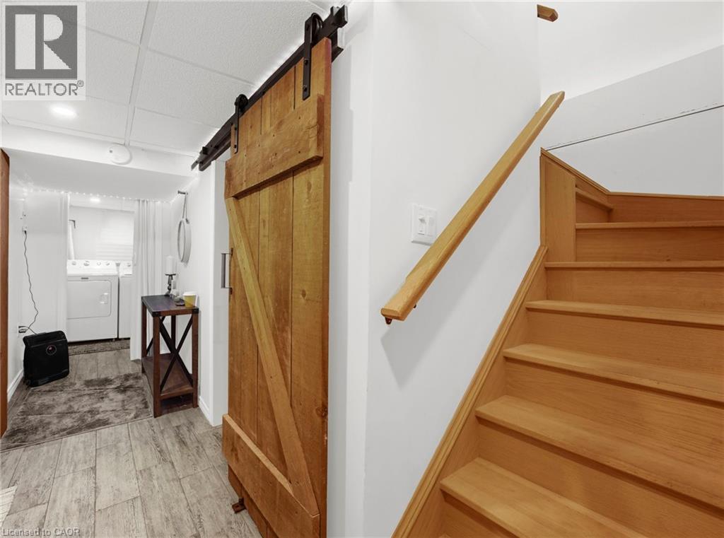 Stairs with a barn door, washer and dryer, wood finished floors, a paneled ceiling, and recessed lighting