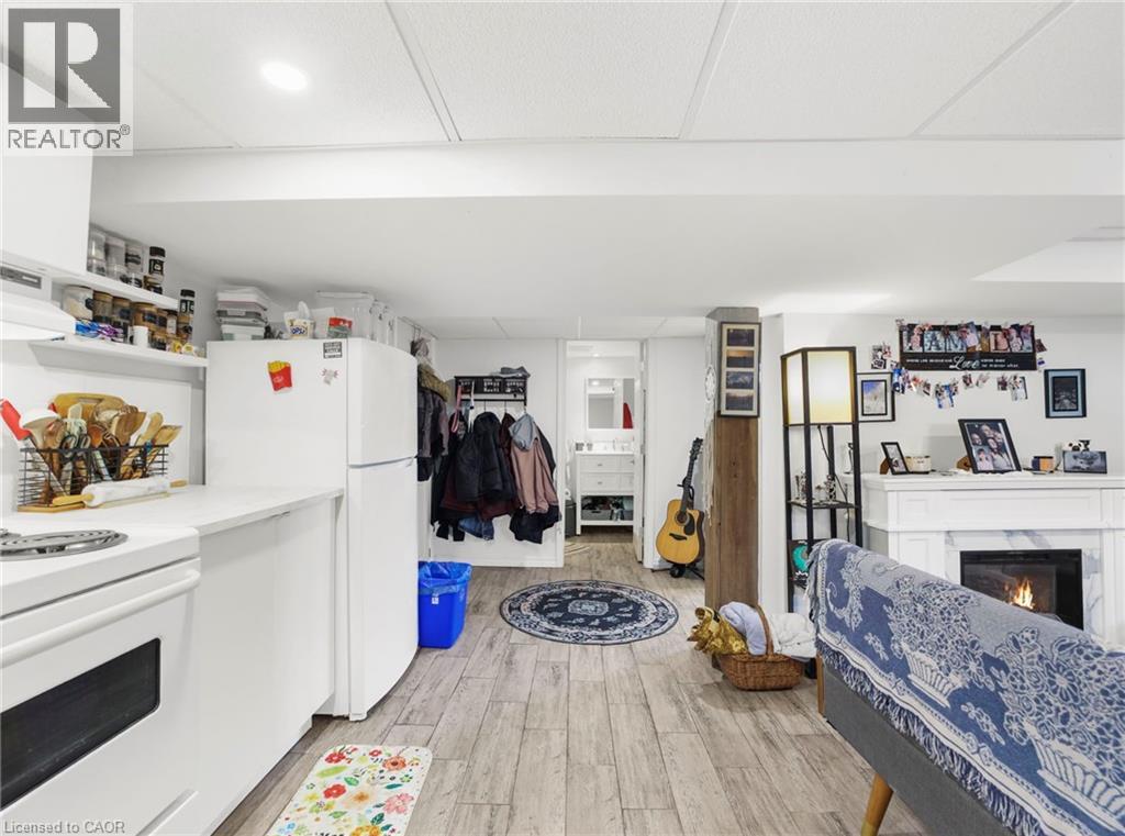 Kitchen featuring white appliances, a warm lit fireplace, light wood-style floors, white cabinetry, and extractor fan