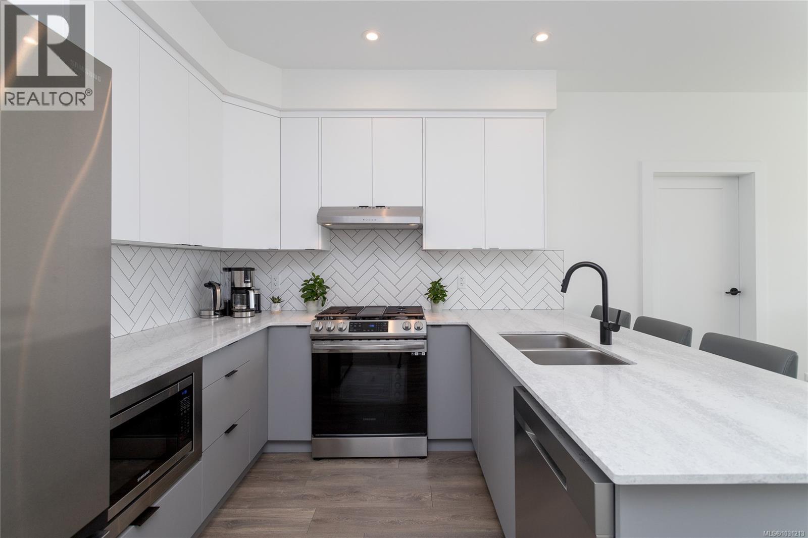 Gorgeous kitchen featuring gas stove, quartz countertops, and herringbone tile back splash.