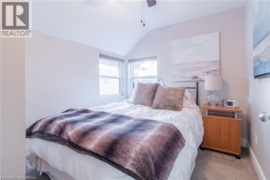 Carpeted bedroom featuring vaulted ceiling and ceiling fan
