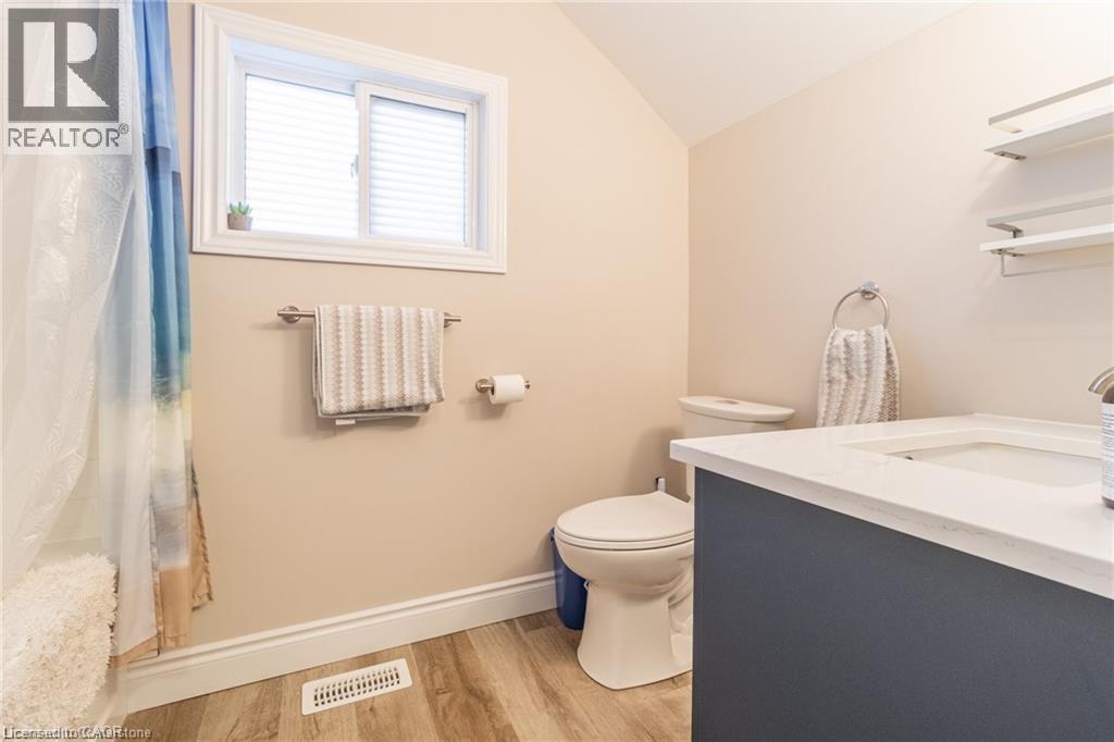 Bathroom featuring vanity, vaulted ceiling, light wood-type flooring, and curtained shower