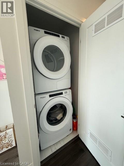 Integrated laundry area featuring a stacked washer and dryer unit, set within a dedicated closet space