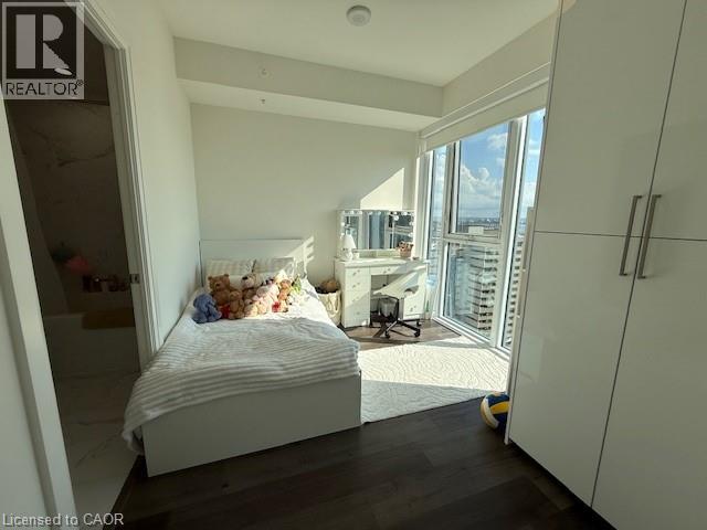 This room features dark hardwood flooring, white walls, and a large window with a city view