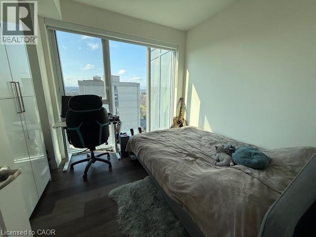 This room features large windows that offer expansive views, dark wood flooring, and ample natural light