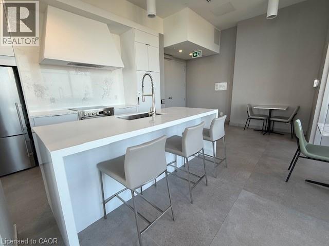 Contemporary kitchen featuring a white island with bar seating, stainless steel appliances, and a matching range hood