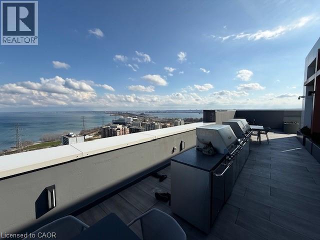 Expansive outdoor terrace featuring an outdoor kitchen with two grills, a dining area, and water views
