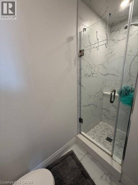 Bathroom featuring a glass-enclosed shower with white marble-style wall tiles and hexagonal floor tiles
